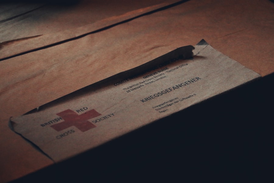 CorsiWeb.eu - Una busta marrone etichettata British Red Cross Society con Kriegsgefangener parzialmente visibile, adagiata su una superficie di legno.